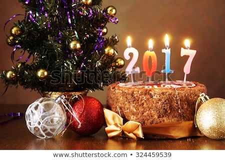 New Year 2017 still life. Chocolate cake and artificial fir tree with burning candles on brown background