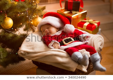 Little baby Santa sleeping under Christmas tree with presents