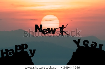 silhouette man jumps to make the word Happy New Year with sunrise