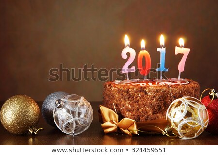 New Year 2017 still life. Chocolate cake and decorative tree balls with burning candles on brown background
