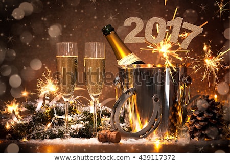 New Years Eve celebration background with pair of flutes and bottle of champagne in bucket and a horseshoe as lucky charm