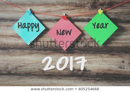 Happy new year 2017 on colorful paper with clothespin hanging on a string with wooden background, retro style